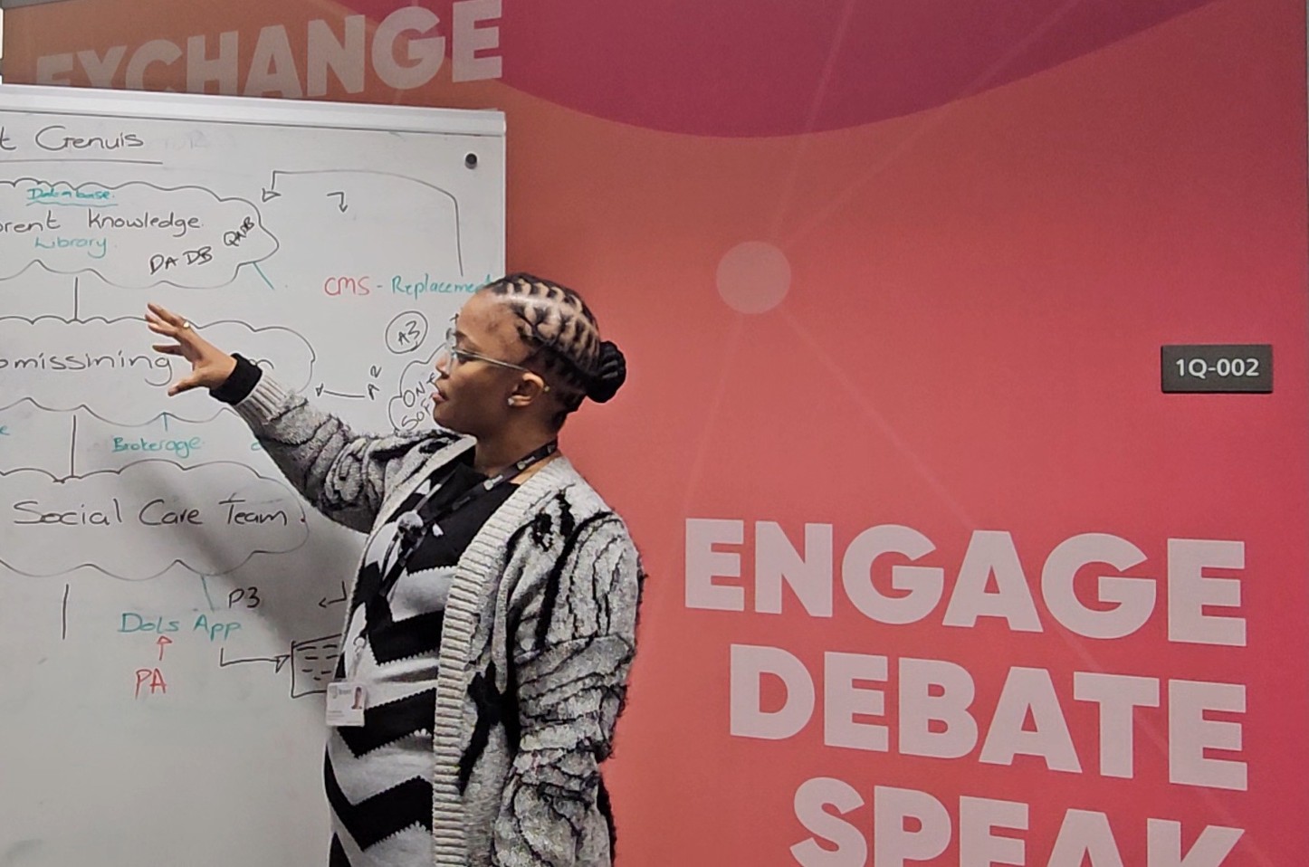 A woman pointing towards a whiteboard