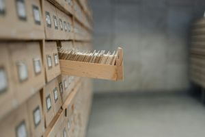 Image of an archive room, with rows of drawers. One drawer is open with folders inside