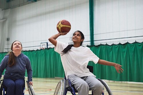 Two girls in wheelchairs playing basketball