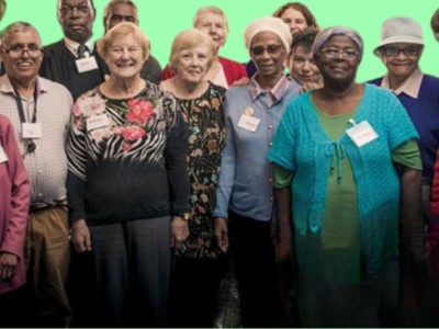 A group of smiling men and women look to the camera