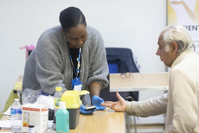 Female social care officer giving resident blood check