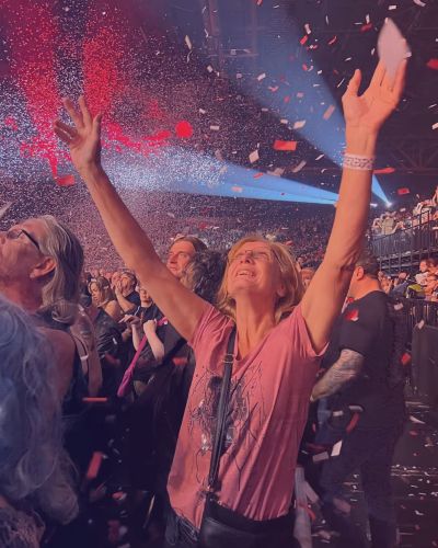 woman at a concert with hands in the air 