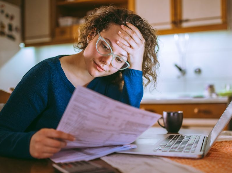 Women reading her utility bill in her kitchen