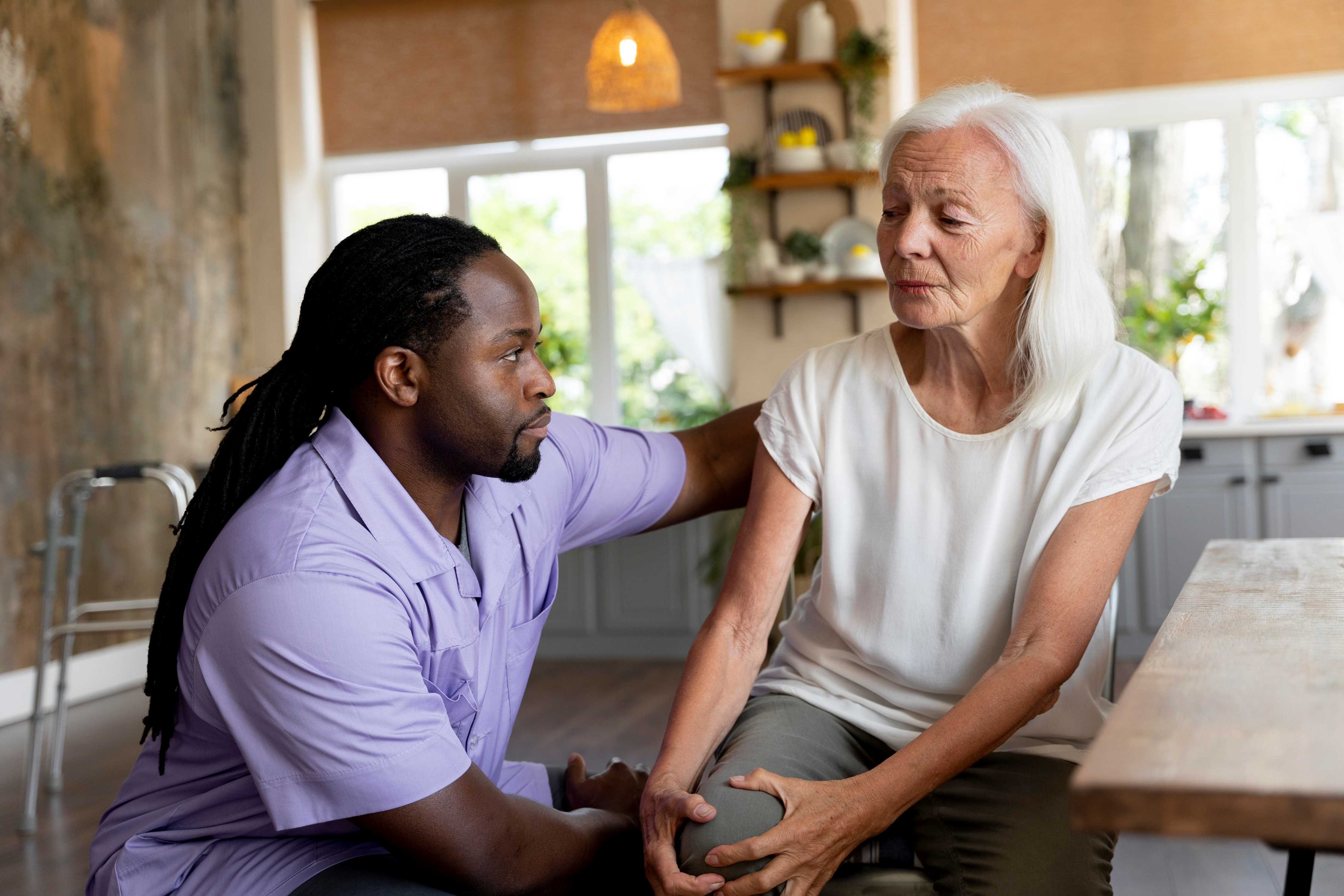 A male social worker-helping a senior woman in her home home