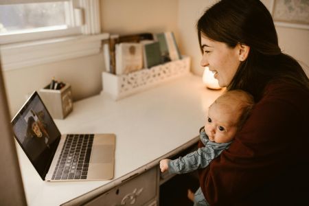 mother holding a baby and talking on computer