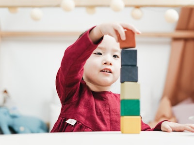 toddler playing with a tower of building blocks