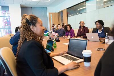 Image of people sitting around a table with laptops.