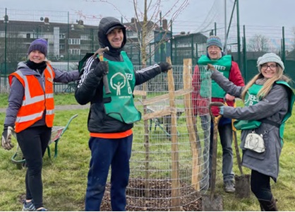 a group of people standing around a planted tree