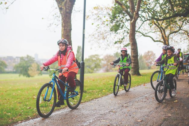 Young children cycling through a park